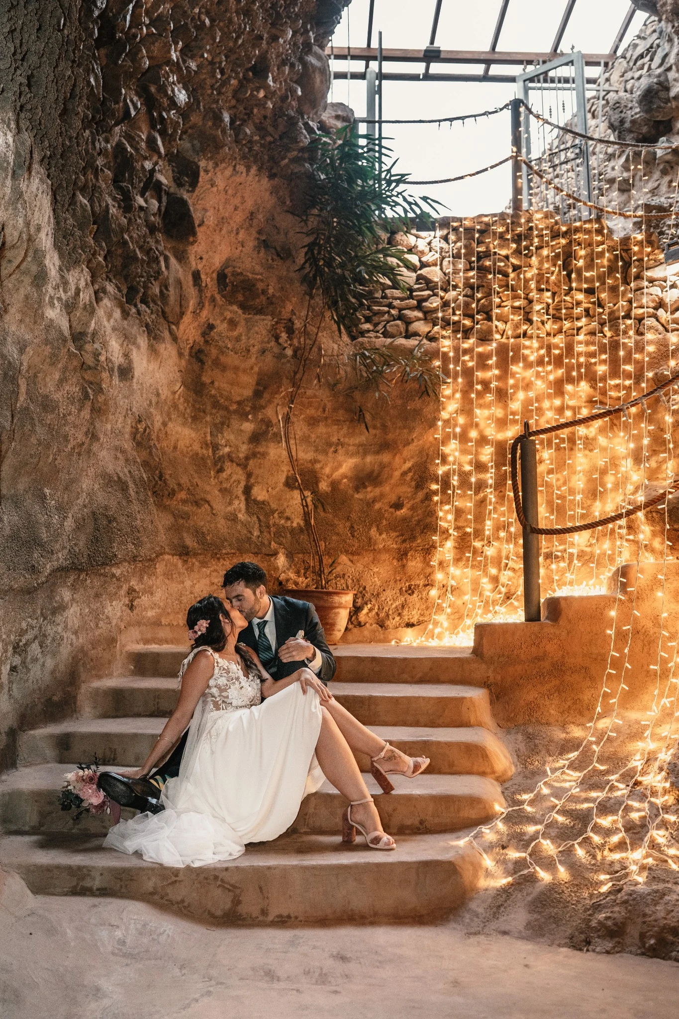 Los novios se besan en las escaleras iluminadas de la cueva durante la celebración