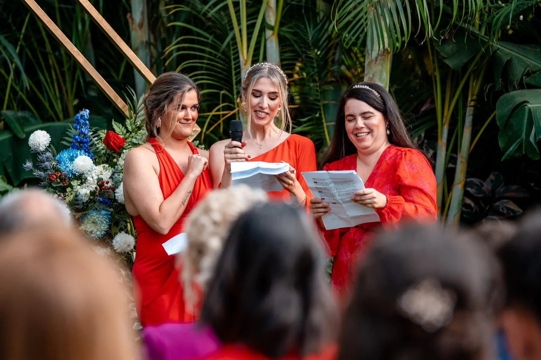 Damas de honor leyendo durante la ceremonia con arco floral