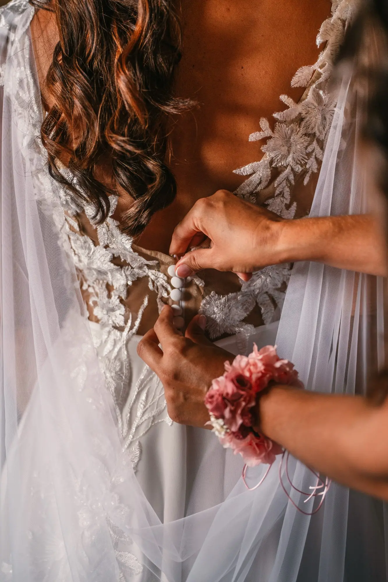 Manos abrochando la espalda del vestido de novia durante los preparativos en Hacienda de Anzo