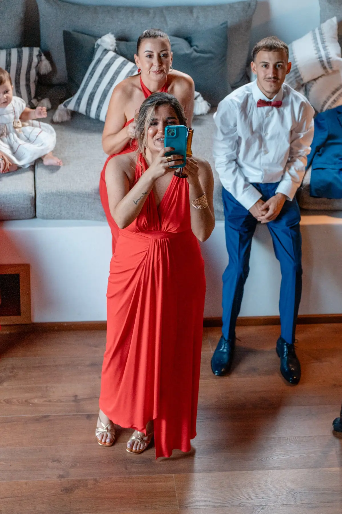 Invitada con vestido rojo con el móvil haciendo foto al novio