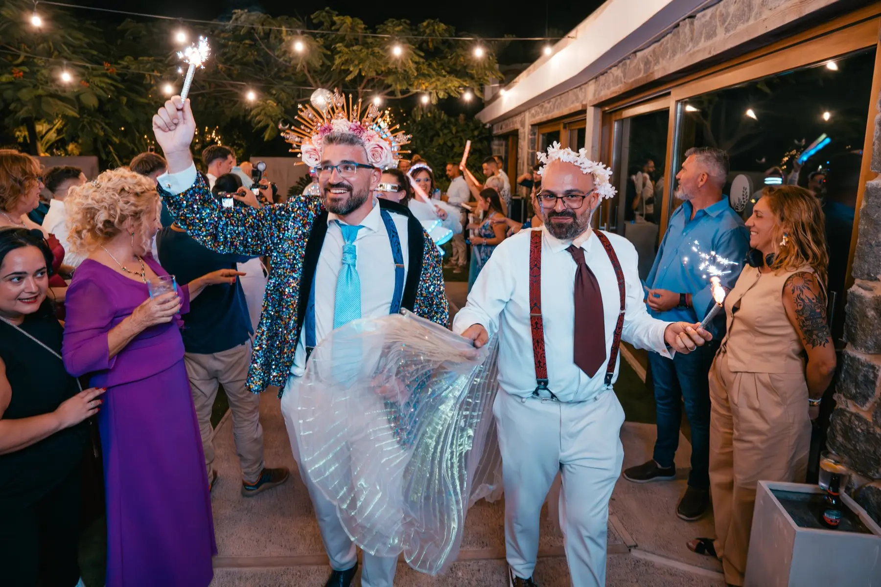 Novios con alas y bengalas bajando escaleras de noche