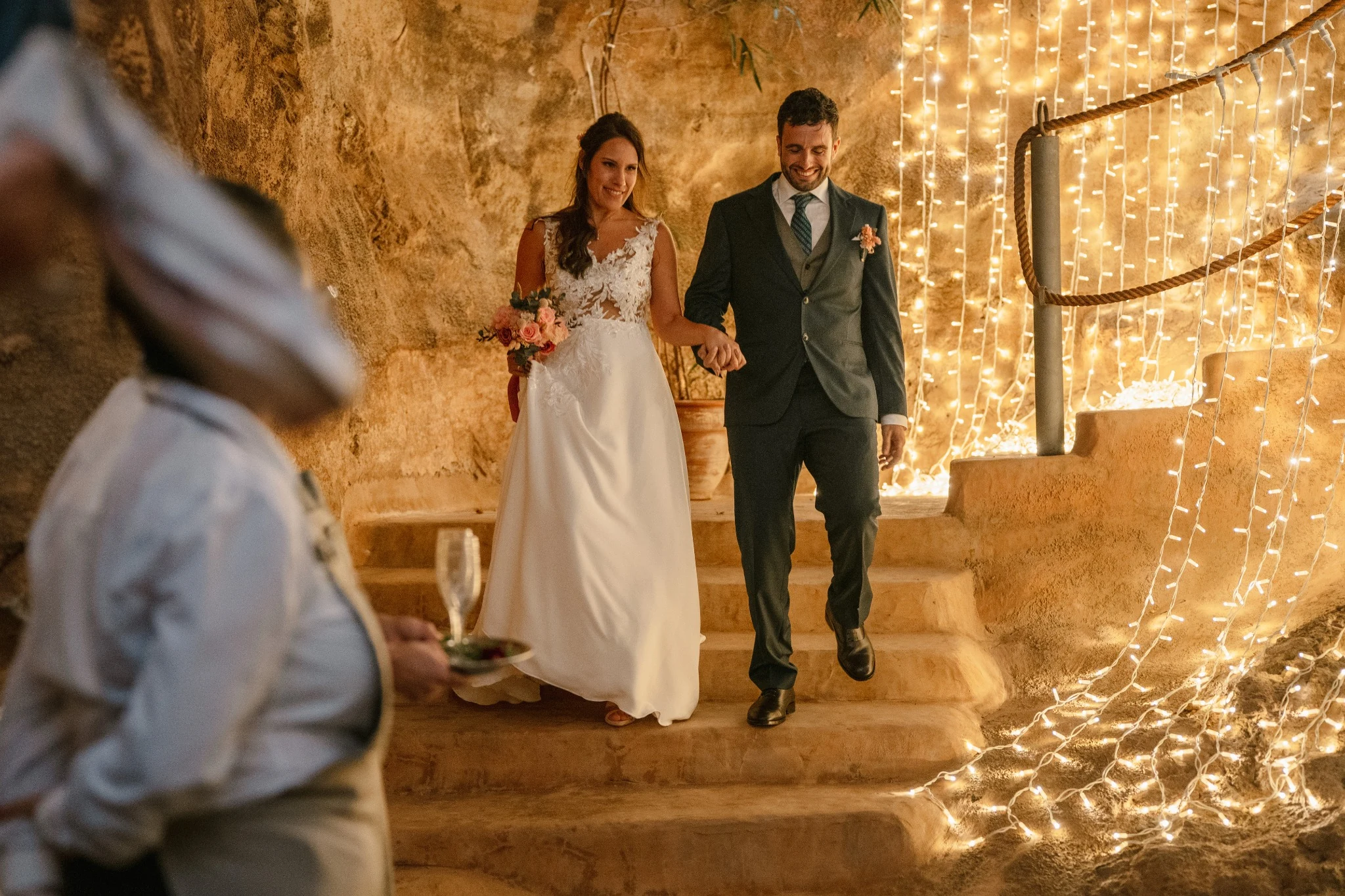 Novios bajando las escaleras de la cueva con iluminación cálida en Hacienda de Anzo