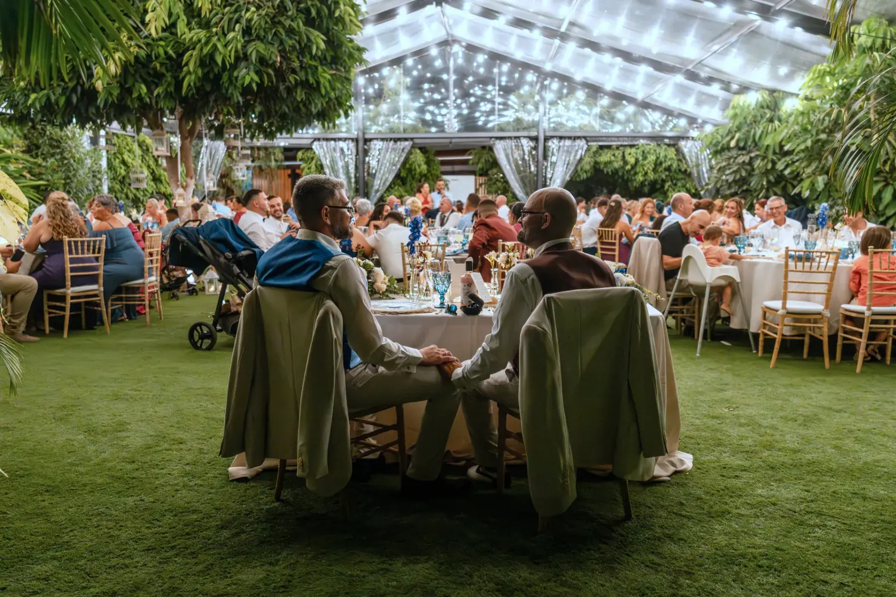 Dos novios de espaldas cogidos de la mano en mesa presidencial