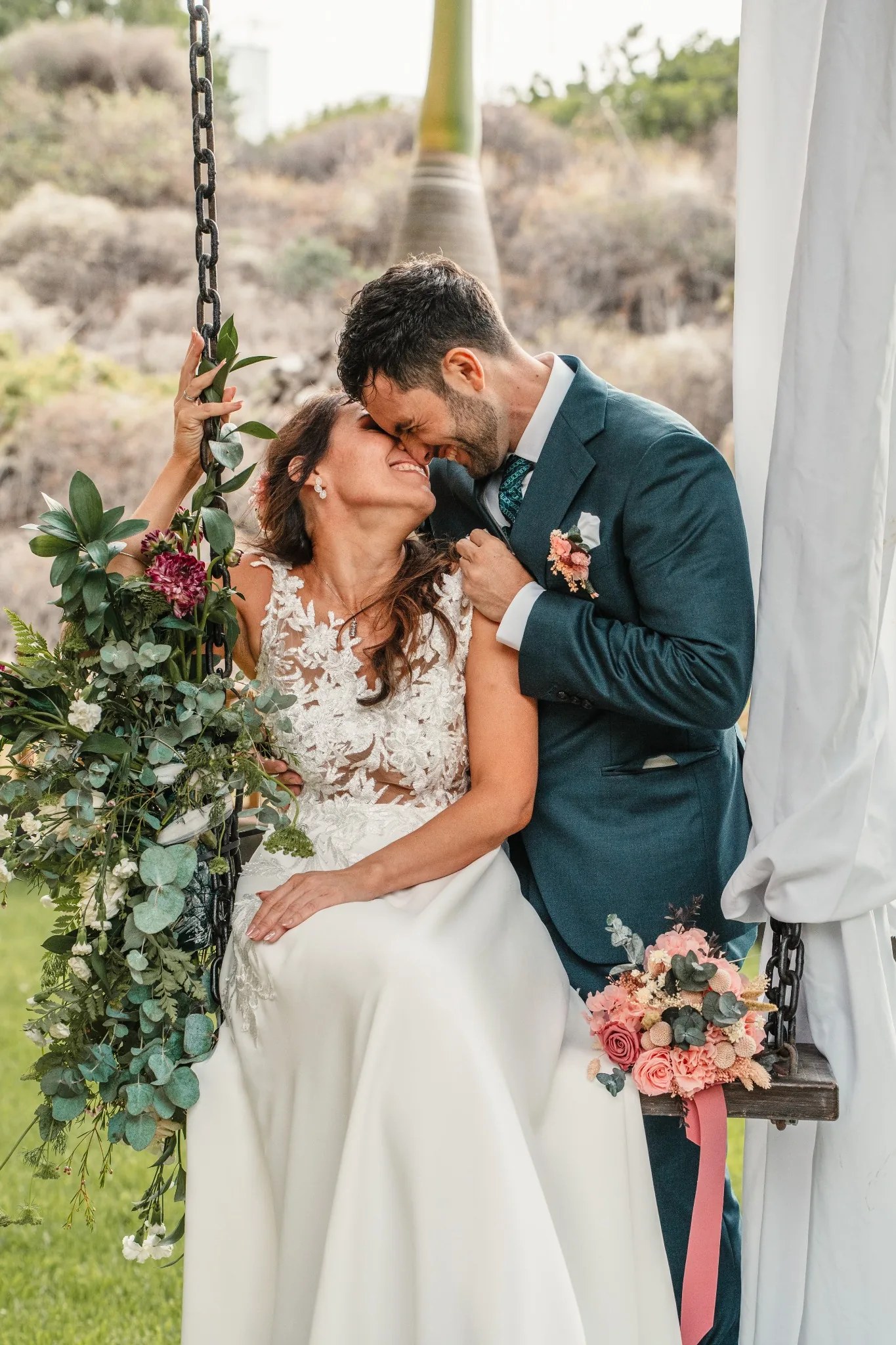 Los novios en un columpio decorado con flores en los jardines de Hacienda Anzo
