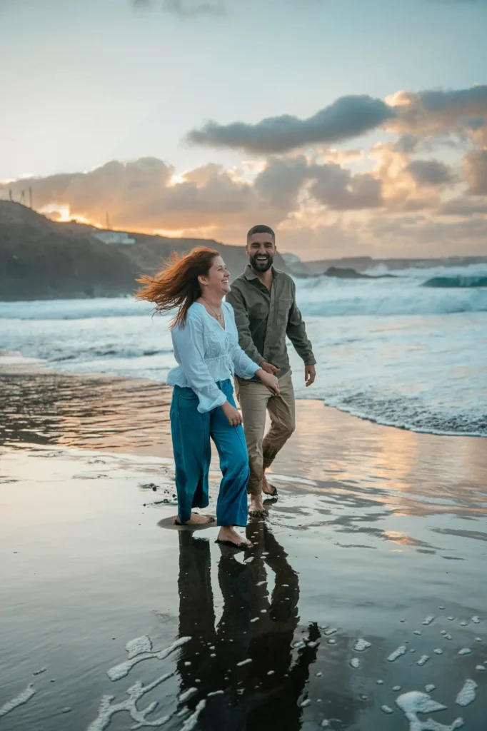 Sesión de fotos de pareja caminando por la playa de arena negra al atardecer en Gran Canaria